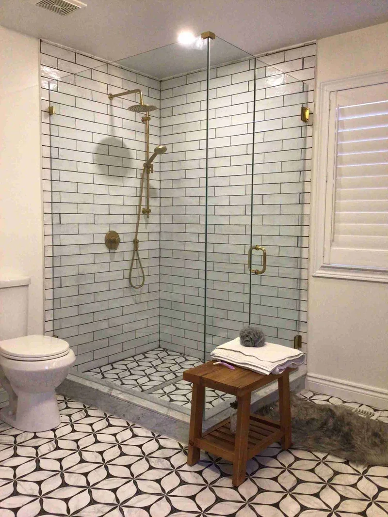 Frameless glass shower enclosure with brass hardware, a shower door service we offer in Whitby